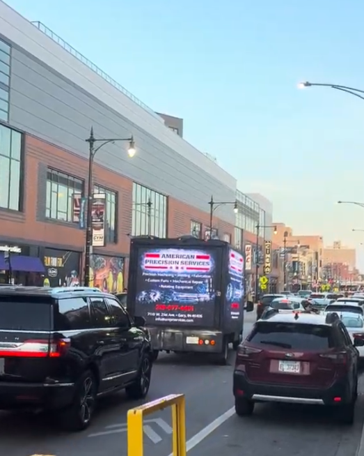 AOTC mobile LED truck for American Precision Services in traffic on a busy Wrigleyville street