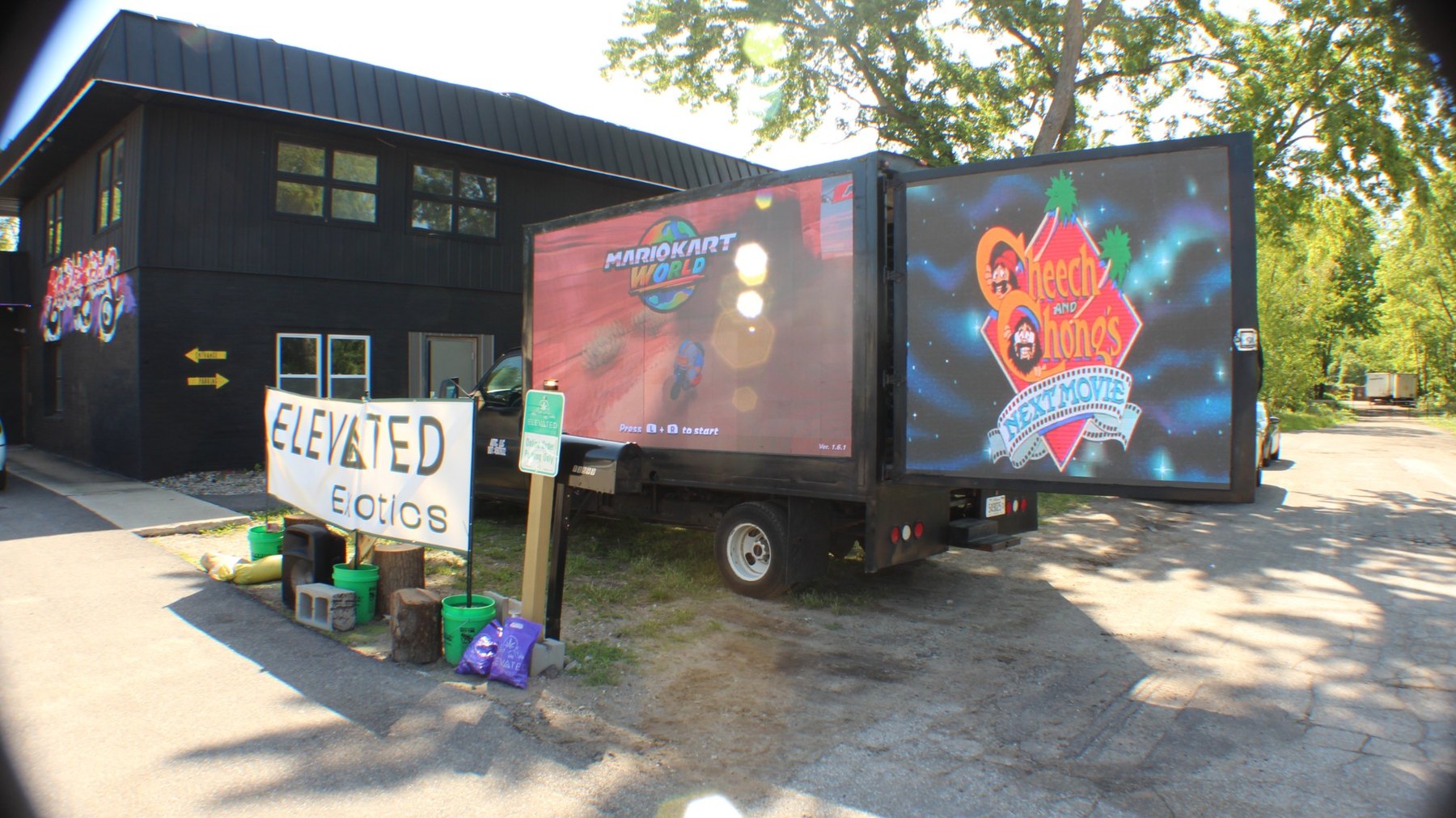 AOTC four-screen LED truck running Mario Kart and Cheech and Chong's Next Movie outside Elevated Exotics with a welcome banner