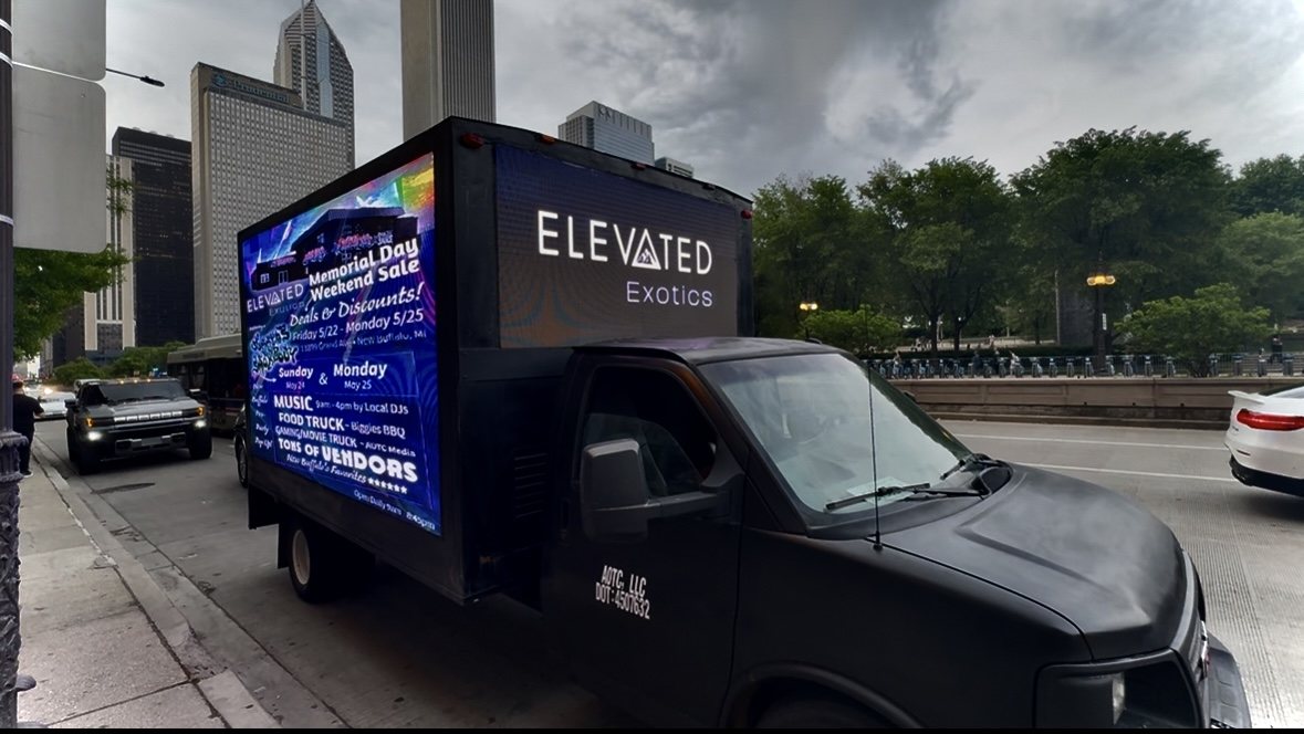 AOTC mobile LED truck for Elevated Exotics on a Chicago street with the skyline behind it
