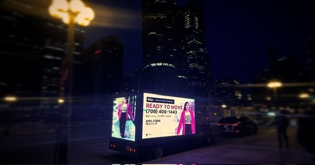AOTC mobile LED truck for Realty of America glowing against the Chicago skyline at night