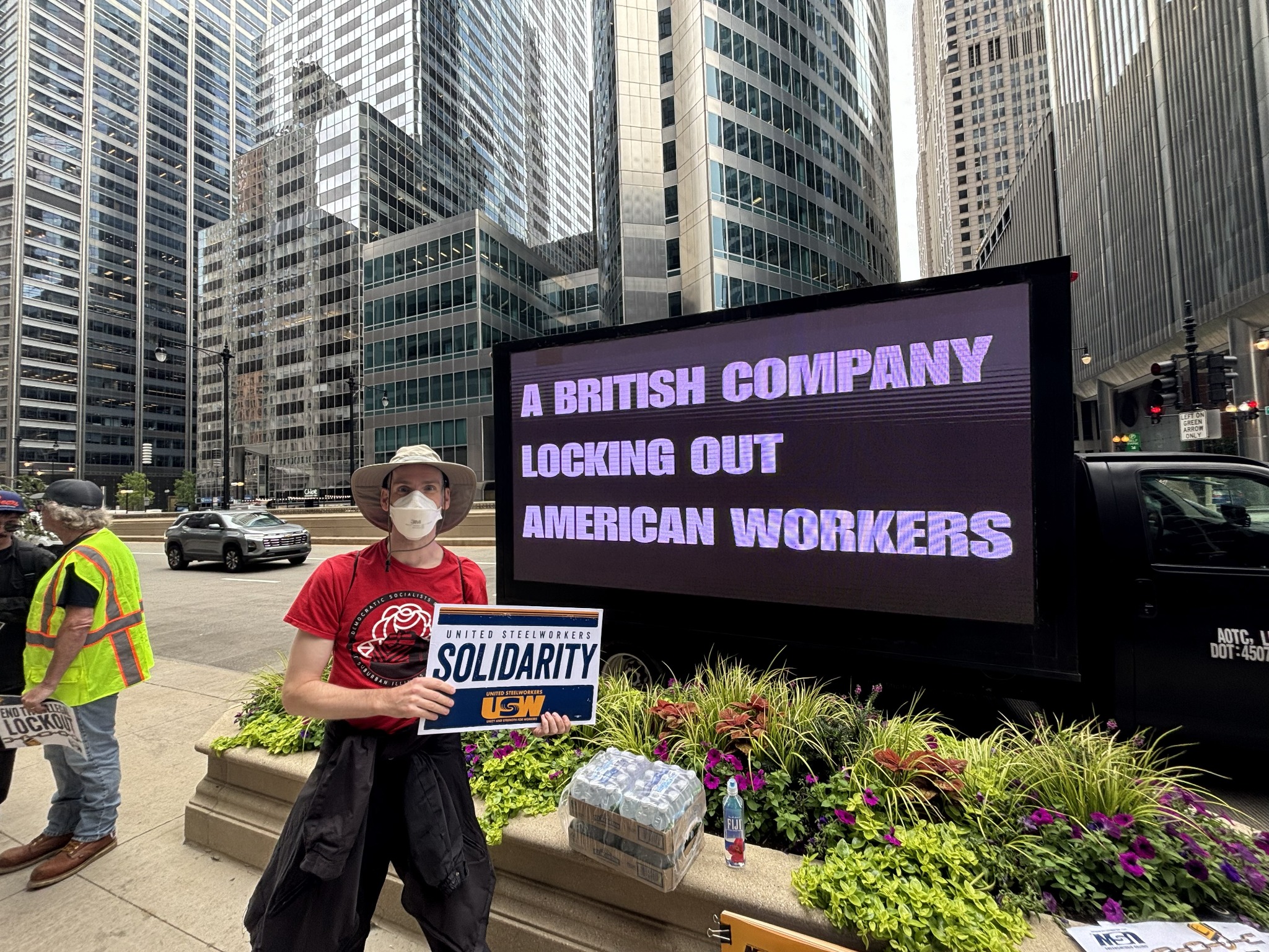 A supporter holding a Solidarity sign in front of the AOTC LED truck among Chicago skyscrapers